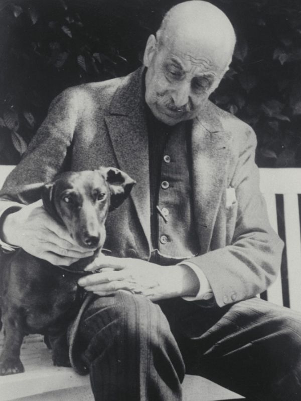Max Liebermann mit einem seiner Dackel auf einer Gartenbank.
